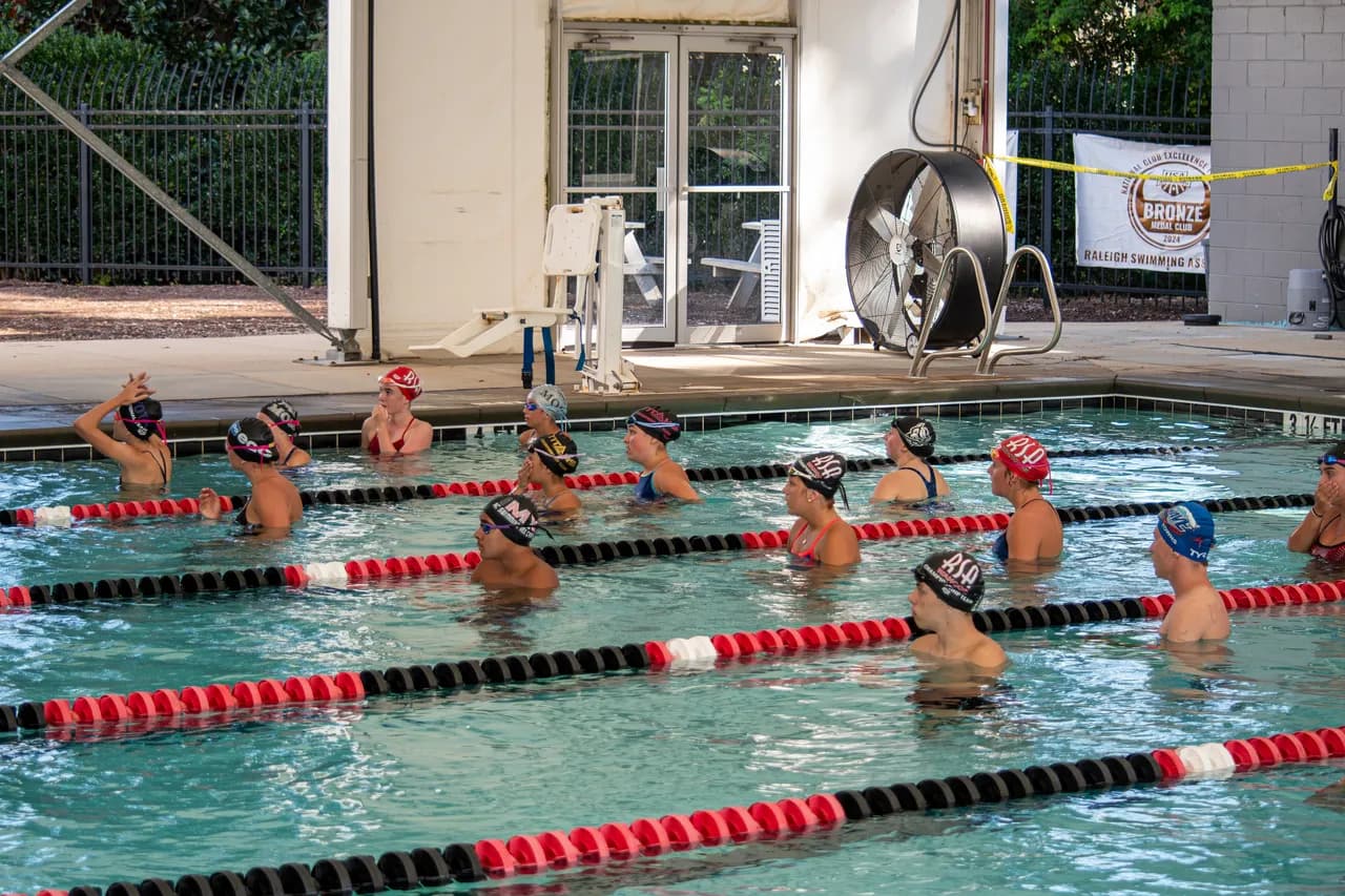 Group of swimmers gather in the pool, listening to coaching instructions during a Wolfpack Elite Speed Force session.