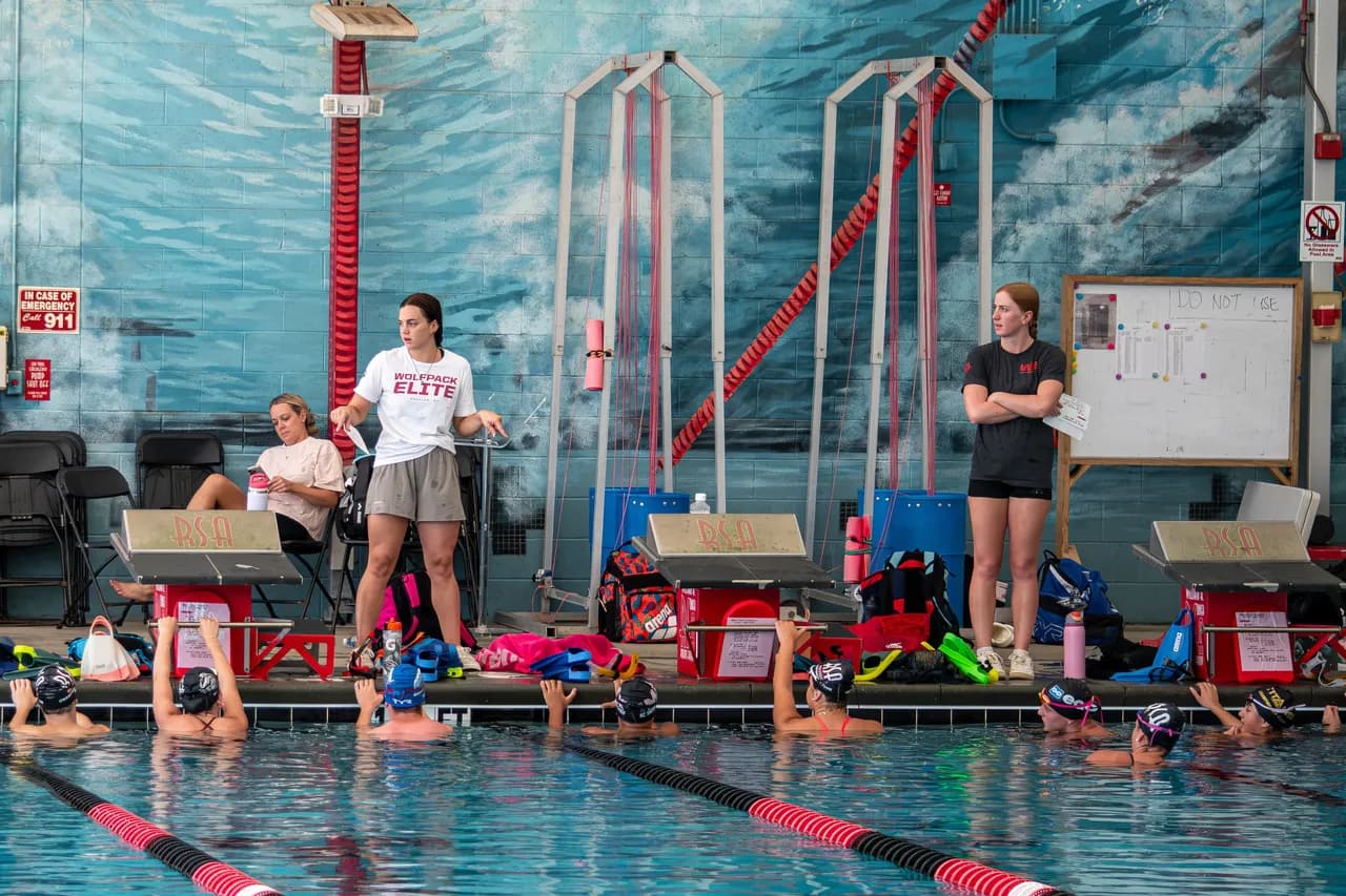 Rhyan White and Kennedy Noble demonstrates a movement to swimmers standing on the pool deck during Speed Force training.