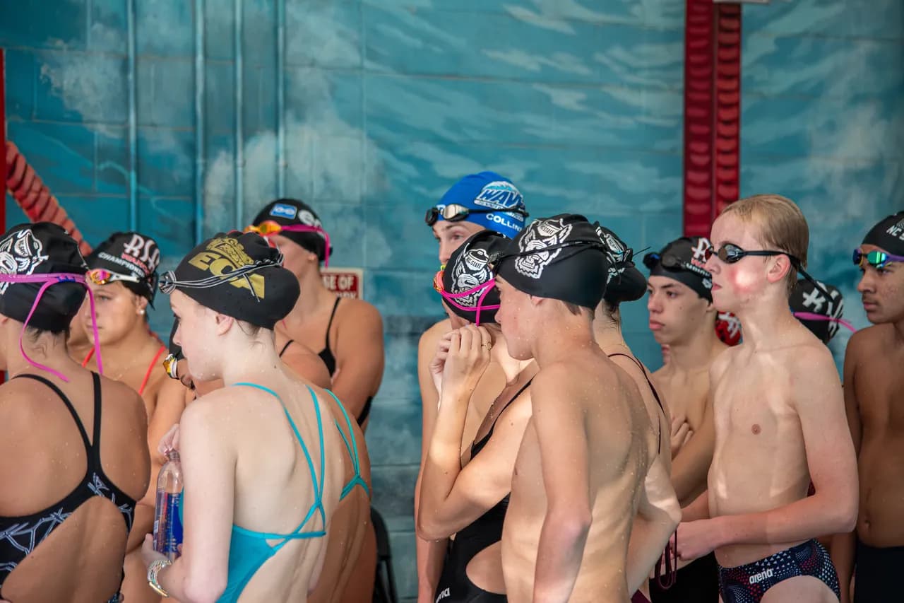 Swimmers gather on the pool deck, listening to instructions during a Wolfpack Elite Speed Force training session.