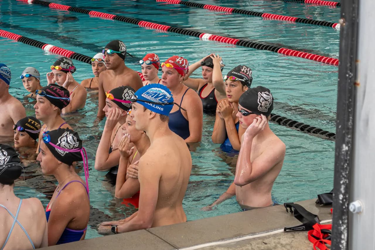 Wolfpack Elite coaches provide instructions to swimmers gathered at the pool wall during a Speed Force training session.